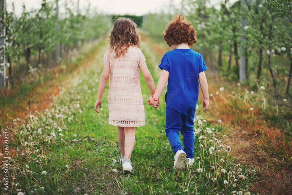 little boy and girl in blooming garden little boy and girl in blooming garden