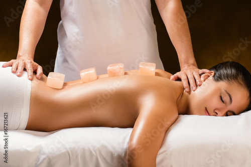 Woman having hot himalayan stone massage in spa.