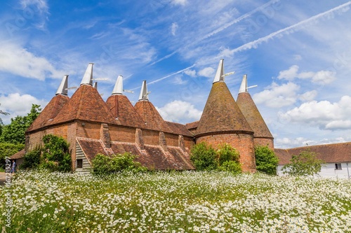 Billede på lærred Oast house with flower field in the front in Sussex, UK