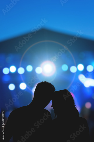 Young couple silhouettes enjoying on the concert.