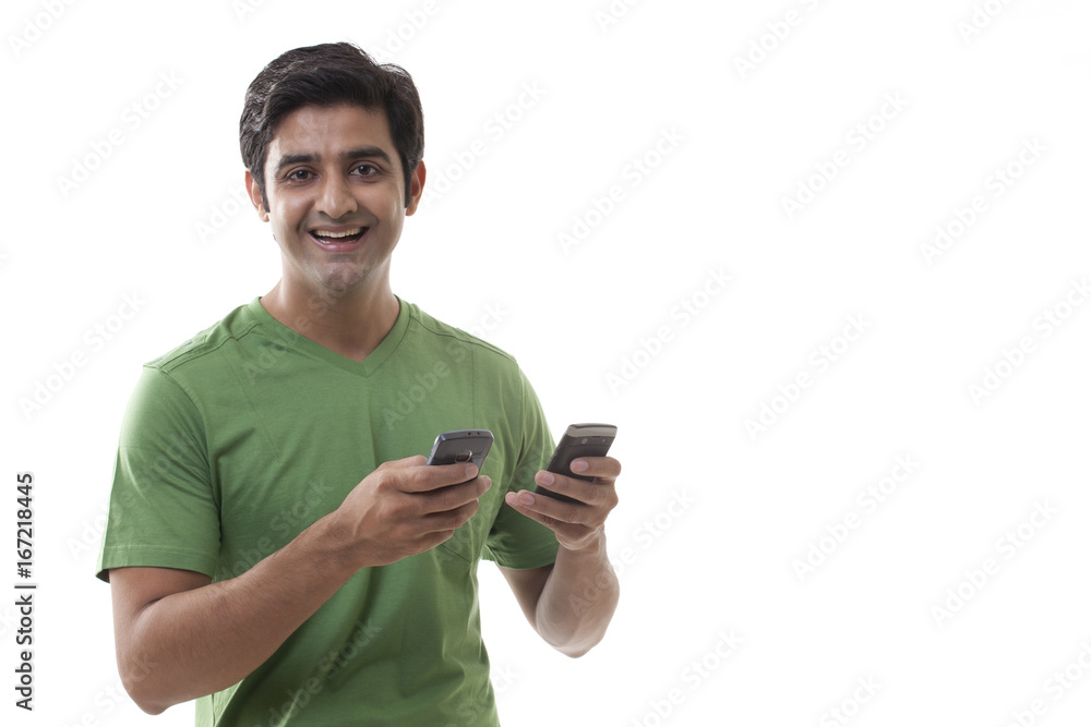 Portrait of handsome man holding cell phones over white background Portrait of handsome man holding cell phones over white background