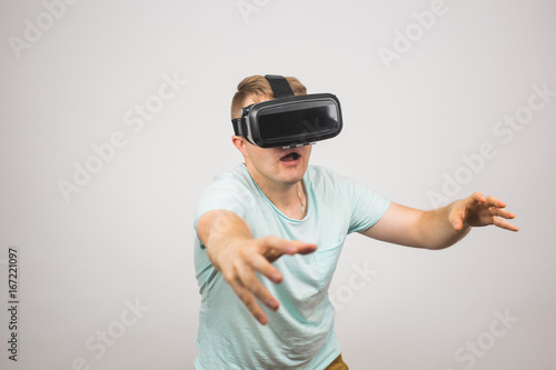 Man wearing virtual reality goggles. Studio shot, gray background.