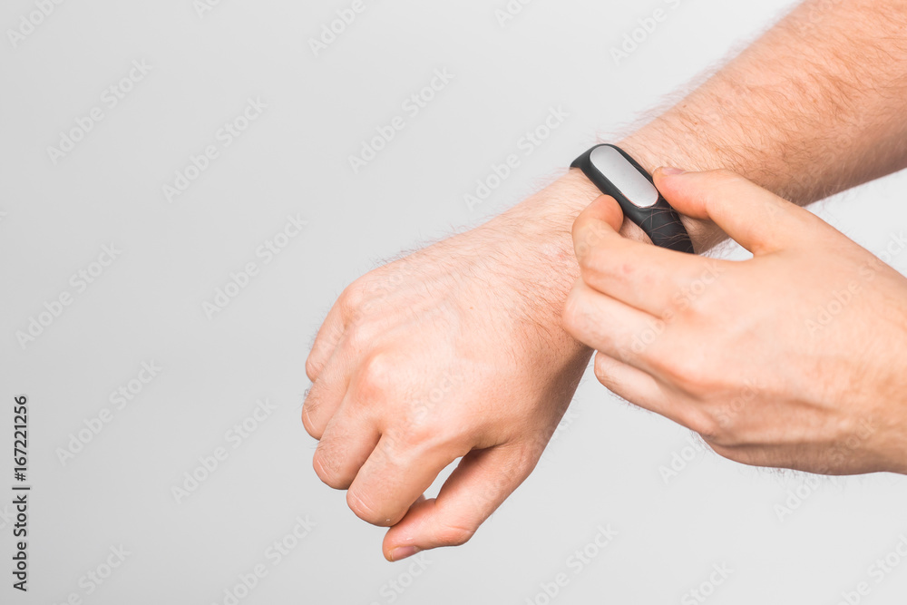 Close-up of man's hand with fitness tracker over grey background Close-up of man's hand with fitness tracker over grey background