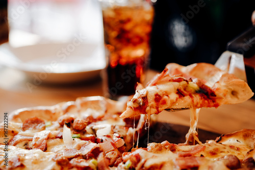 Slice of pizza cheese crust seafood topping sauce. with bell pepper vegetables delicious tasty fast food italian traditional and soft drink carbonated fresh on wooden board table classic in side view