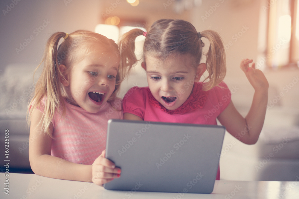 Two little sisters using tablet. Two little sisters using tablet.