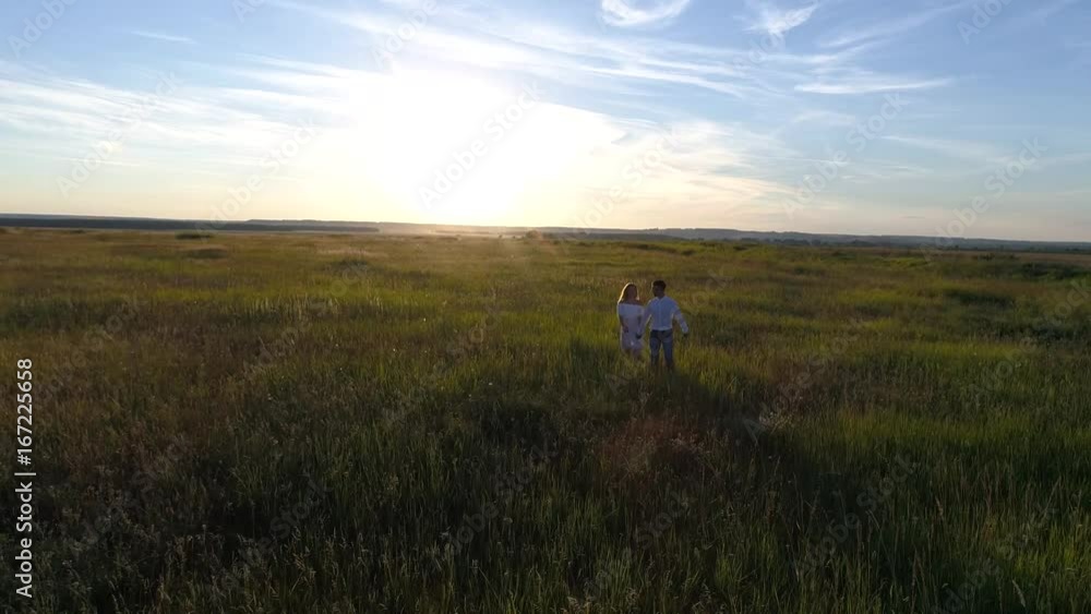 Aerial photography of a young couple running across the field towards the sunset Aerial photography of a young couple running across the field towards the sunset