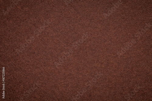 Texture of old dark brown paper background, closeup. Structure of dense umber cardboard