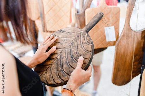 Woman customer choose a handmade wooden board at the sale at the market photo