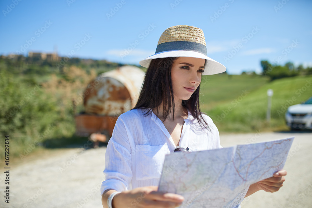 A tourist with a map at the car checks the route to the destination
