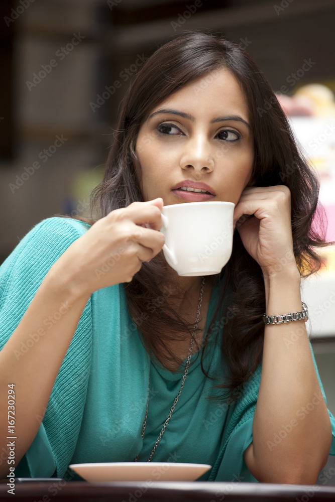 Young woman looking away while drinking tea Young woman looking away while drinking tea