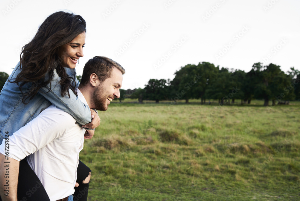Happy young man giving his girlfriend a piggyback ride Happy young man giving his girlfriend a piggyback ride