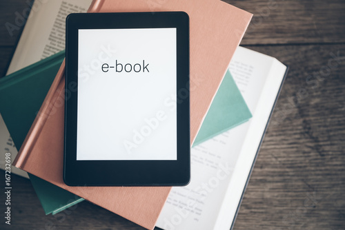 e-book reader on a stack of books on rustic wooden table concept photo