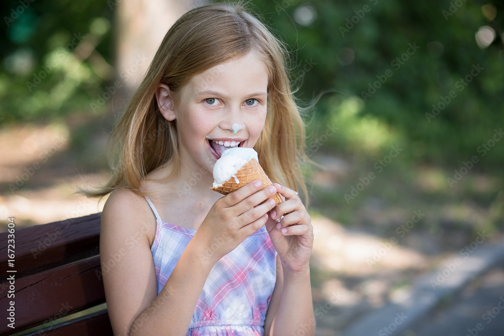 Little girl happy to eat ice cream. Summer, child girl enjoying her ice cream while sitting on a bench. Little girl happy to eat ice cream. Summer, child girl enjoying her ice cream while sitting on a bench.