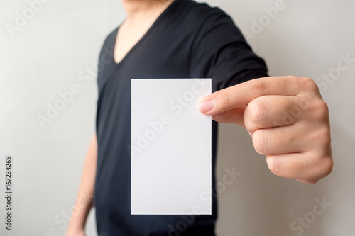 Close up hand of casual man black shirt holding business card on concrete wall background
