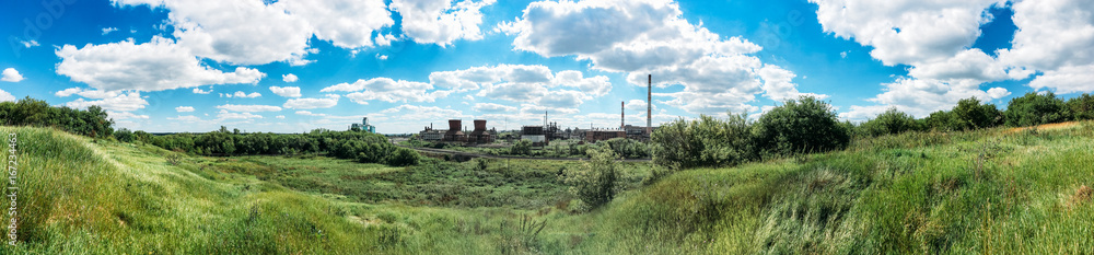 Panorama of green hills and industrial plant with chimneys 