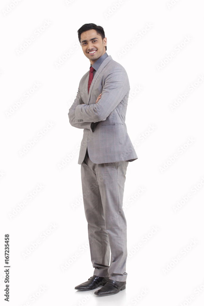 Full length portrait of happy young businessman with arms crossed standing against white background Full length portrait of happy young businessman with arms crossed standing against white background