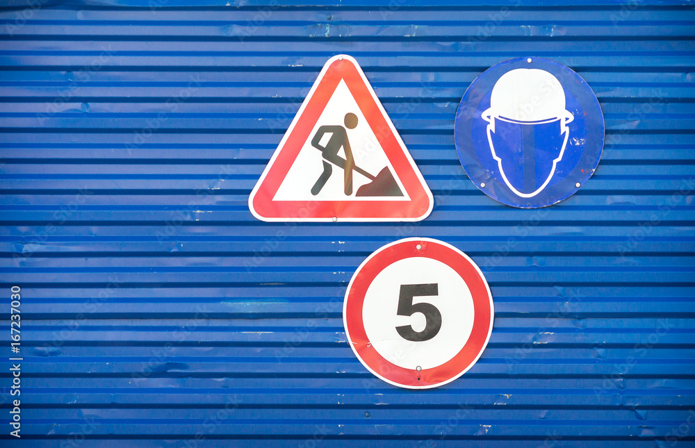 Road signs against a blue metal fence
Road signs against a blue metal fence