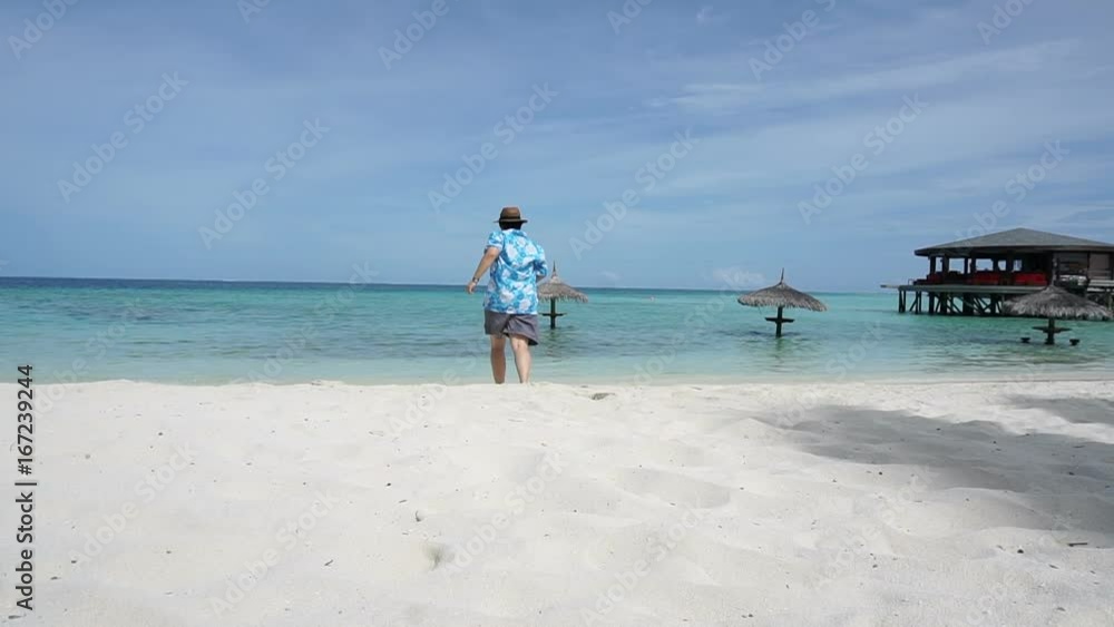 Asian tourist running to beautiful Maldives clear sea. Enjoying her vacation at luxury resort Asian tourist running to beautiful Maldives clear sea. Enjoying her vacation at luxury resort