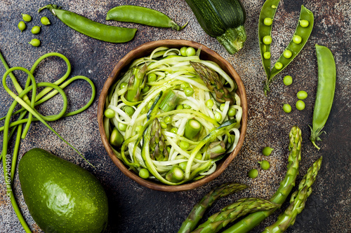 Zucchini spaghetti or noodles (zoodles) bowl with green veggies and garlic scape pesto. Top view, overhead photo