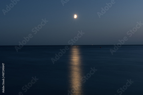 Foto At night a white moon over the sea with a reflection and a path з