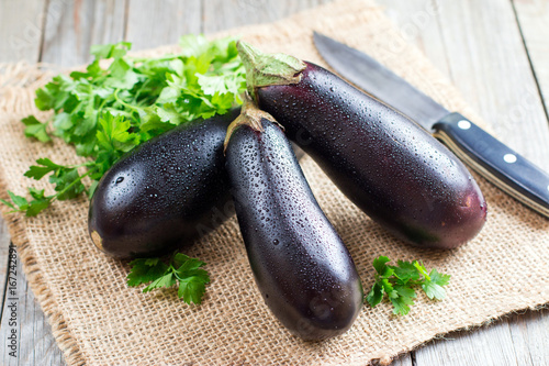 Fresh eggplant with a knife on wooden background