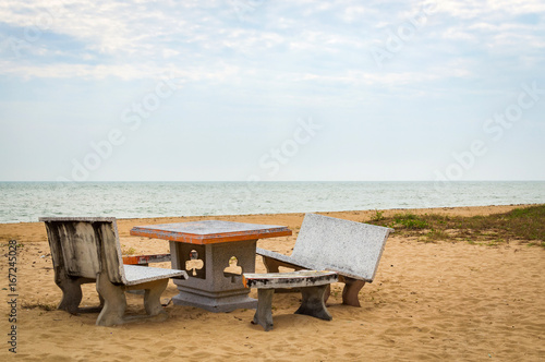 Patio with stone furniture, chairs and table on sandy beach