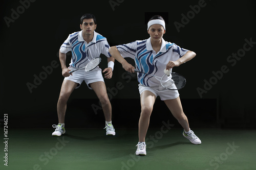Portrait of man and woman playing badminton doubles at court © IndiaPix