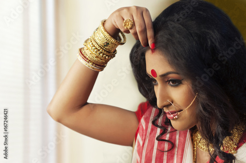 Bengali woman putting sindoor on her forehead photo