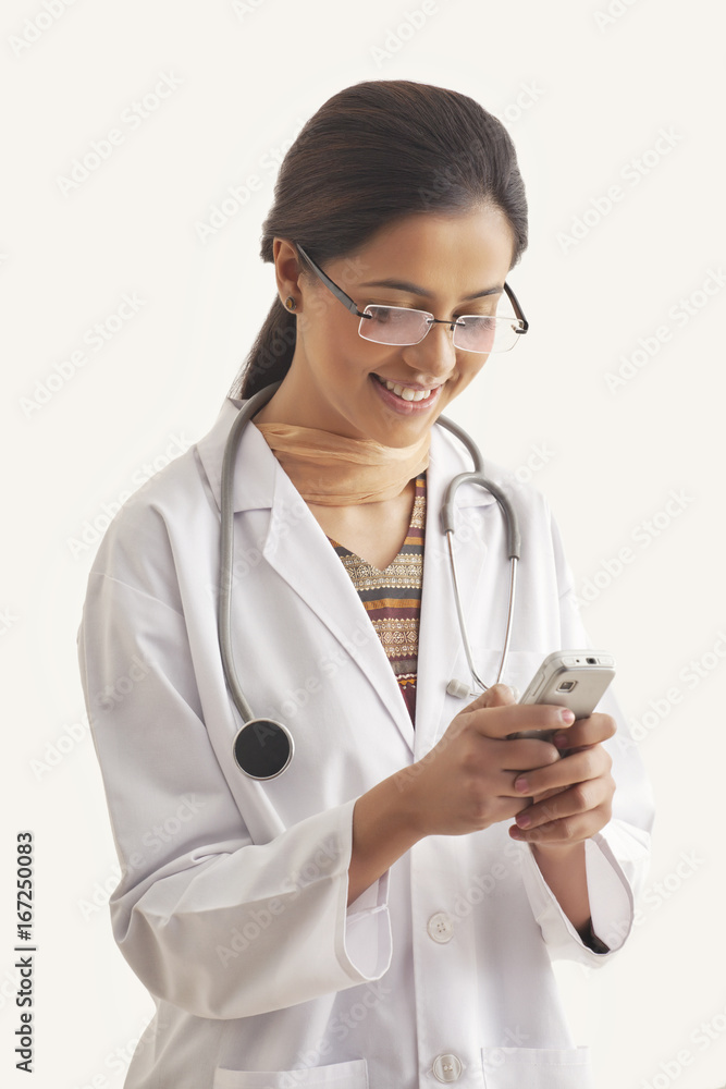 Happy young female doctor text messaging on cell phone isolated over white background Happy young female doctor text messaging on cell phone isolated over white background