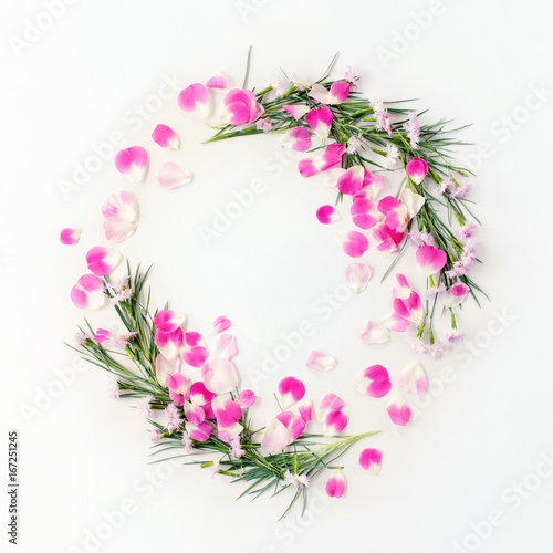 Flat lay frame wreath with carnation flowers and rose petals and green leaves on white. Top view holiday concept.