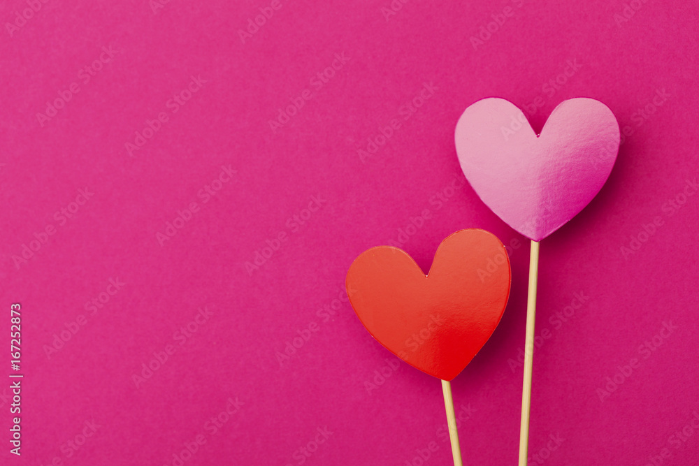 Paper hearts on a stick over a bright pink background