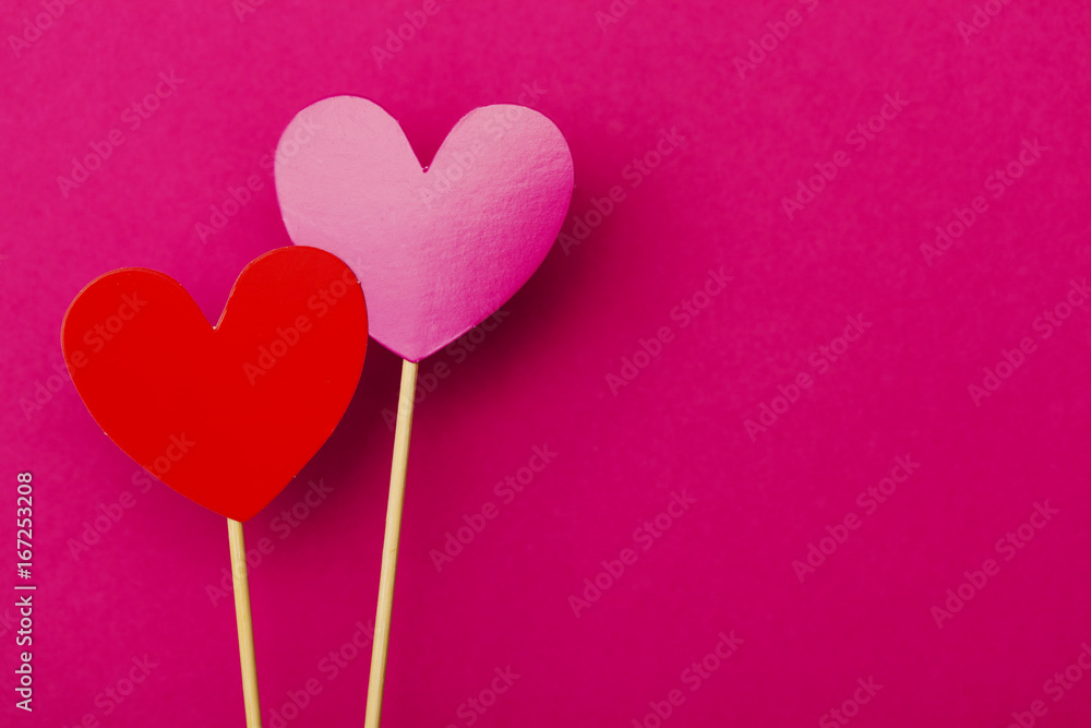 Paper hearts on a stick over a bright pink background