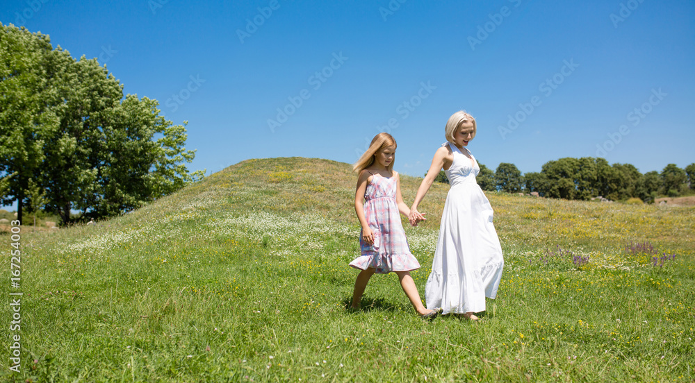 Sunny day, mother and little girl walking in the field. Happy mom and daughter spending time together outdoors. Sunny day, mother and little girl walking in the field. Happy mom and daughter spending time together outdoors.