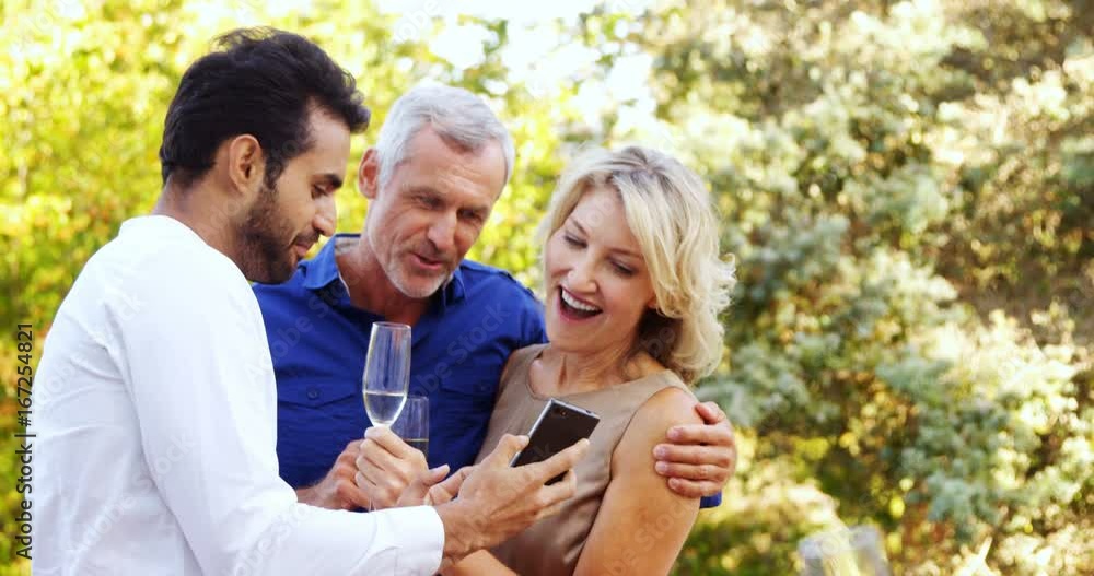 Man showing mobile phone to couple in balcony Man showing mobile phone to couple in balcony
