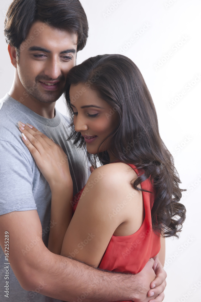 Fototapeta premium Romantic young couple embracing against white background