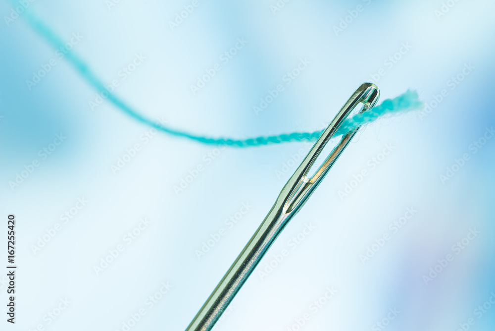 A blue thread goes through the needle eye A blue thread goes through the needle eye