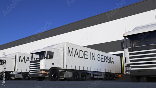 Freight semi trucks with MADE IN SERBIA caption on the trailer loading or unloading. Road cargo transportation 3D rendering