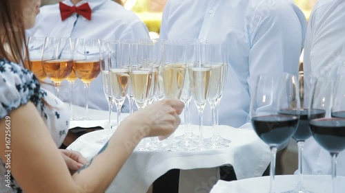 Waiters greet guests with alcoholic drinks. Champagne, red, white wine on trays photo