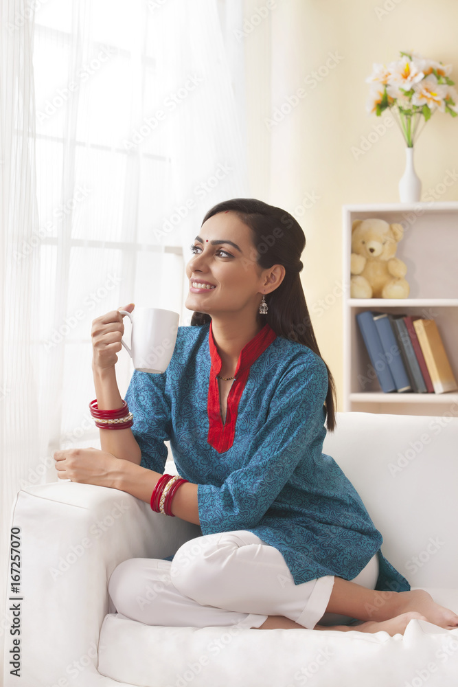 Married Indian woman having coffee in living room Married Indian woman having coffee in living room