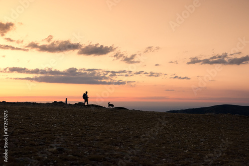 Hiker and his dog walk down the mountain in an amazing sunset. Navacerrada, Spain. © carlosobriganti
