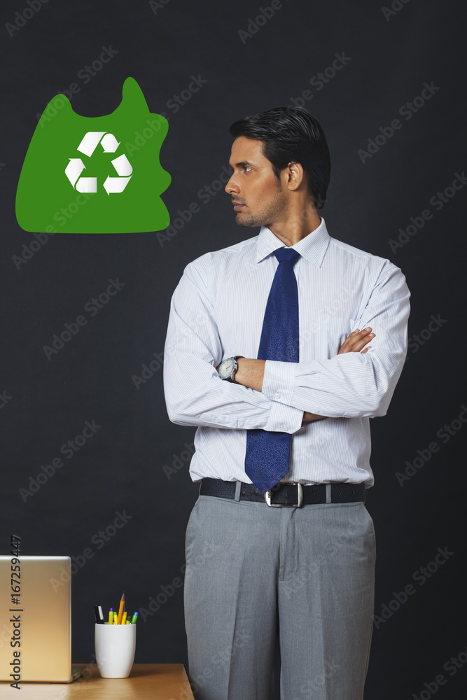 Digitally generated image of businessman looking at recycling symbol in office Digitally generated image of businessman looking at recycling symbol in office