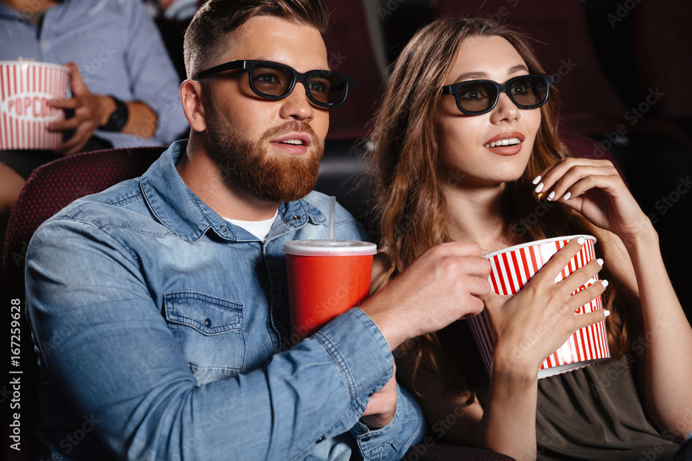 Fototapeta premium Concentrated friends loving couple sitting in cinema