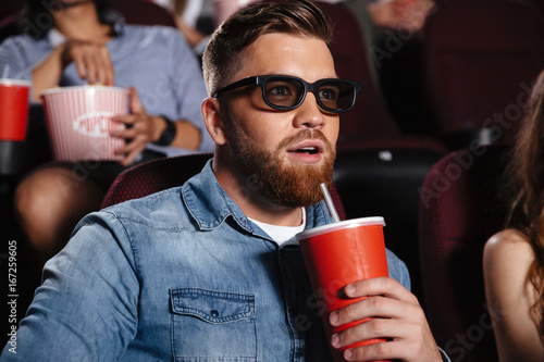 Concentrated young man sitting in cinema