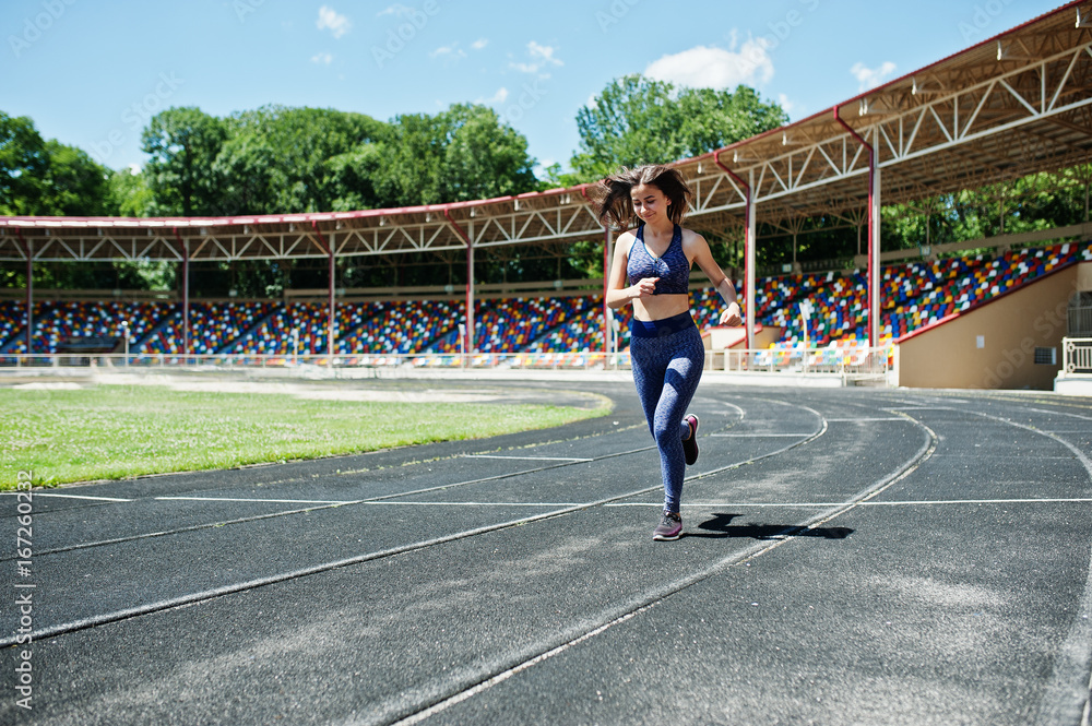 Fototapeta premium Portrait of a strong fit girl in sportswear running in the stadium.
