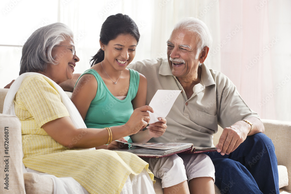 Granddaughter looking at a photo album with her grandparents Granddaughter looking at a photo album with her grandparents