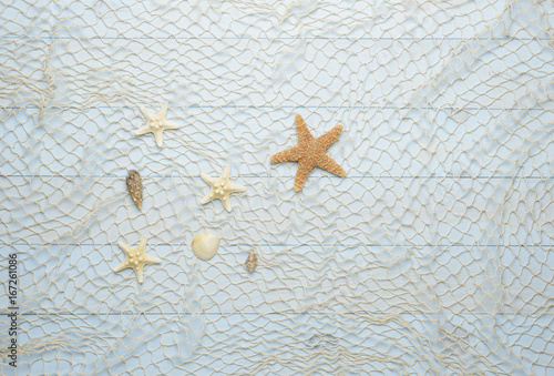 Conchas, estrella de mar y caracolas marinos sobre fondo de madera azul con red de pescar