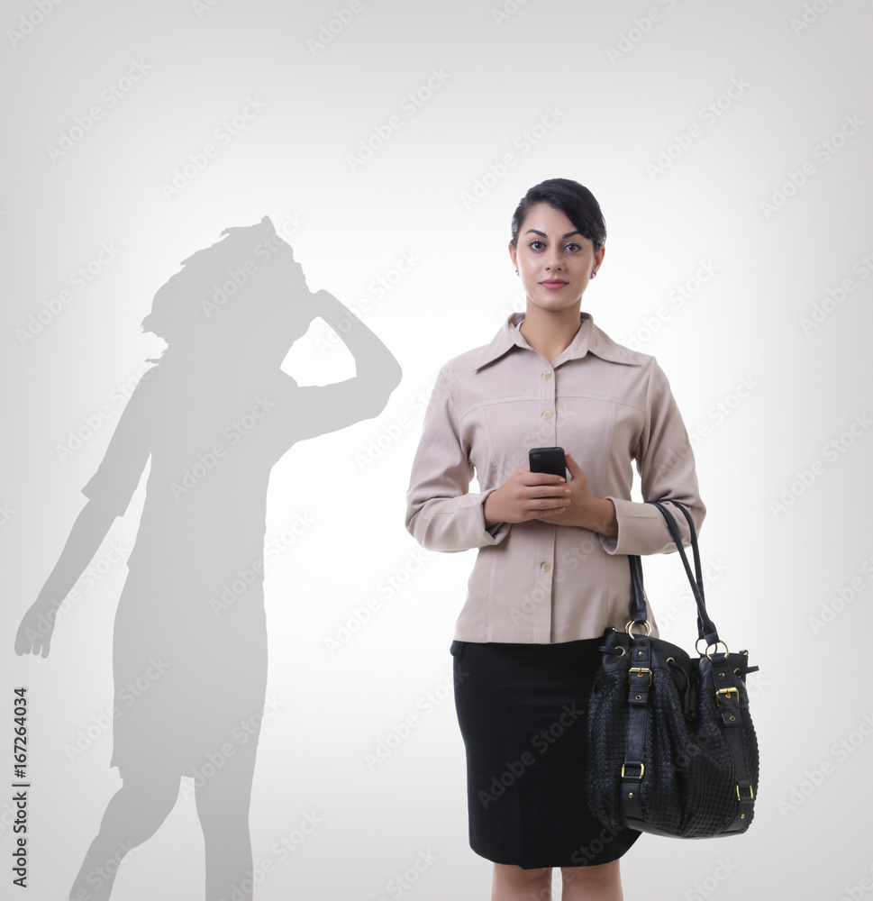 Confident businesswoman standing in front of shadow dancing over gray background Confident businesswoman standing in front of shadow dancing over gray background