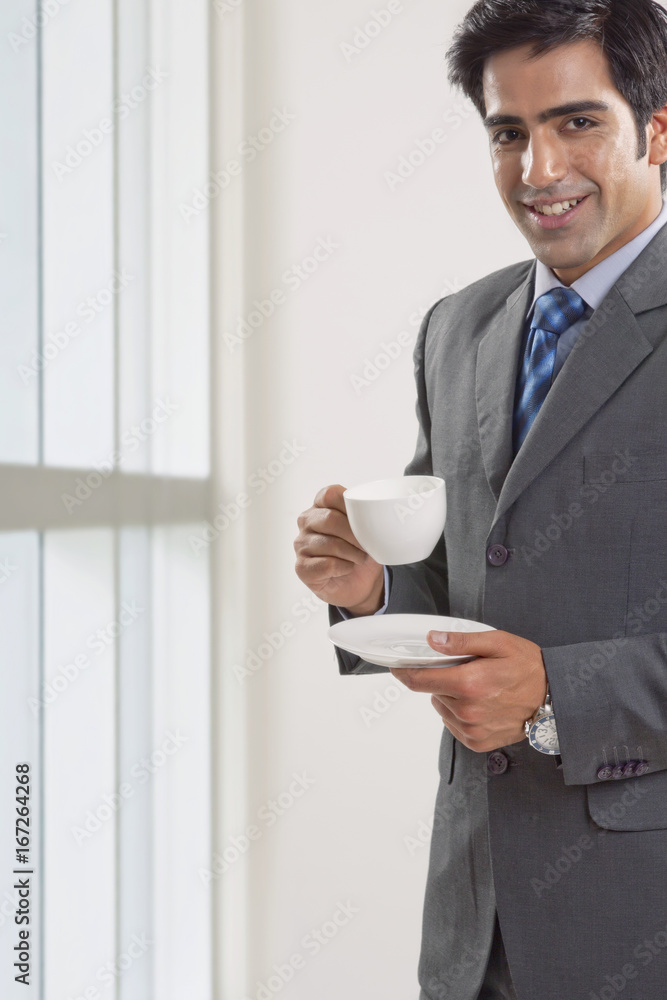 Portrait of young businessman having coffee cup in office Portrait of young businessman having coffee cup in office