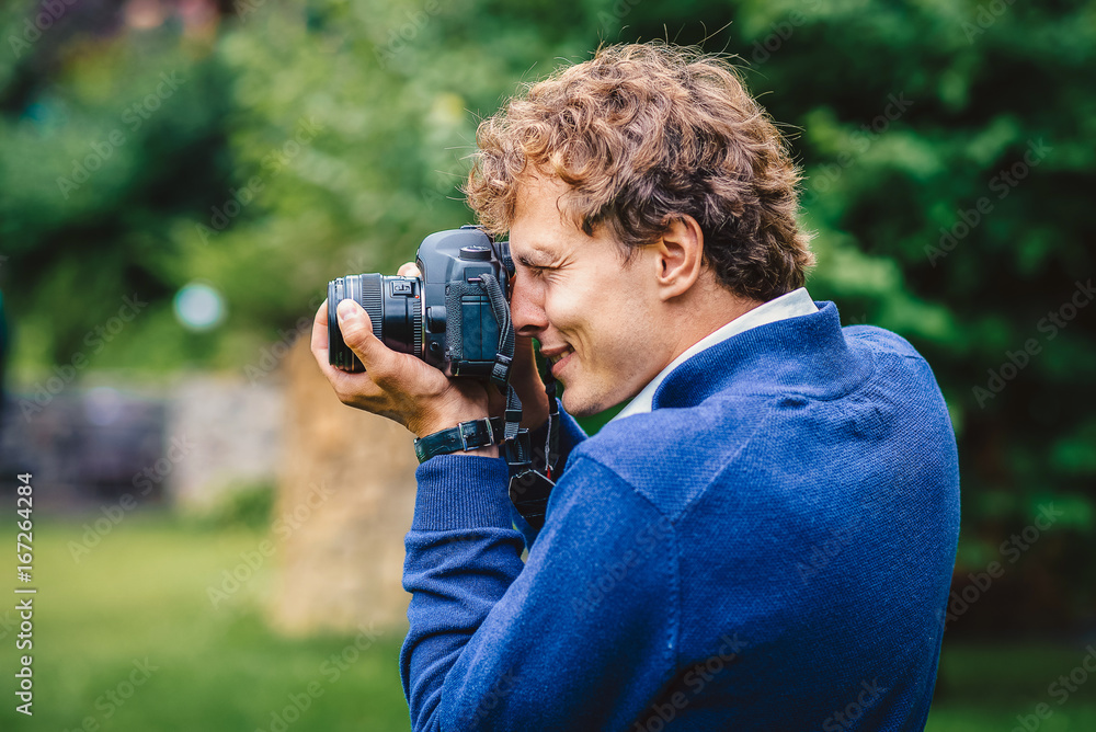 A wedding photographer takes pictures in nature. Portrait of the photographer in action.