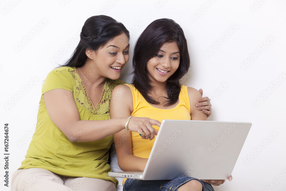 Mother and daughter using computer together over white background Mother and daughter using computer together over white background